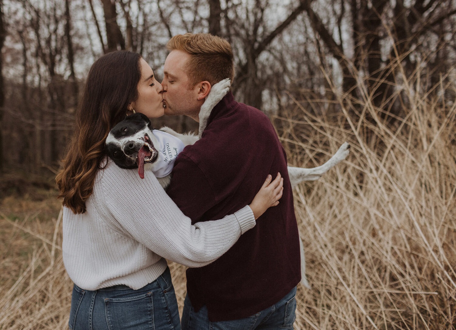 couple kissing with their dog during engagement session 