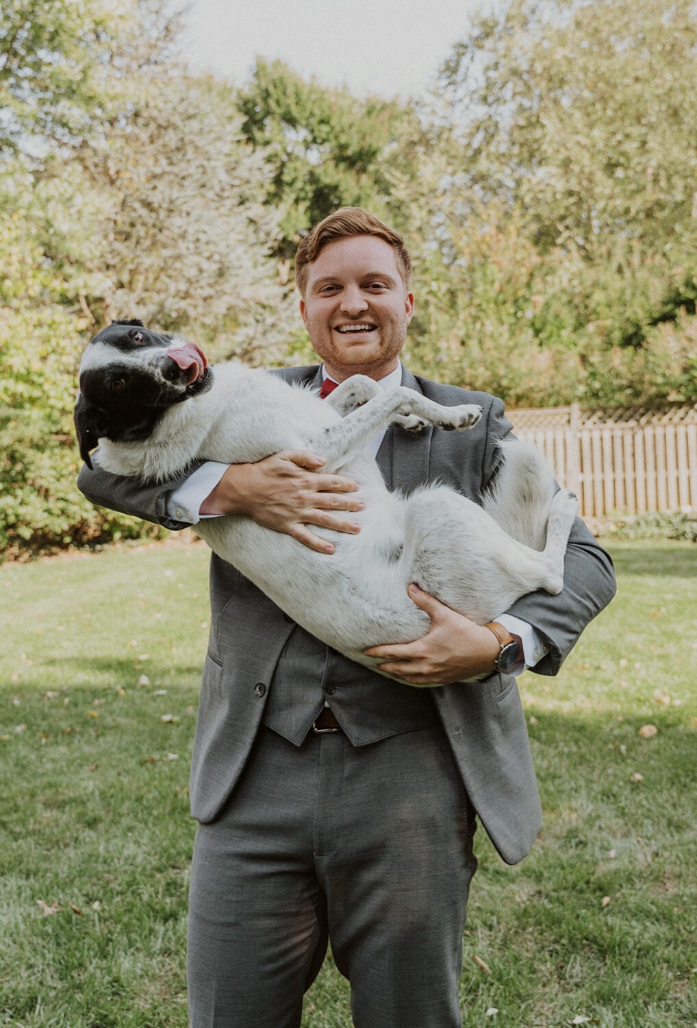 groom poses with dog before wedding ceremony