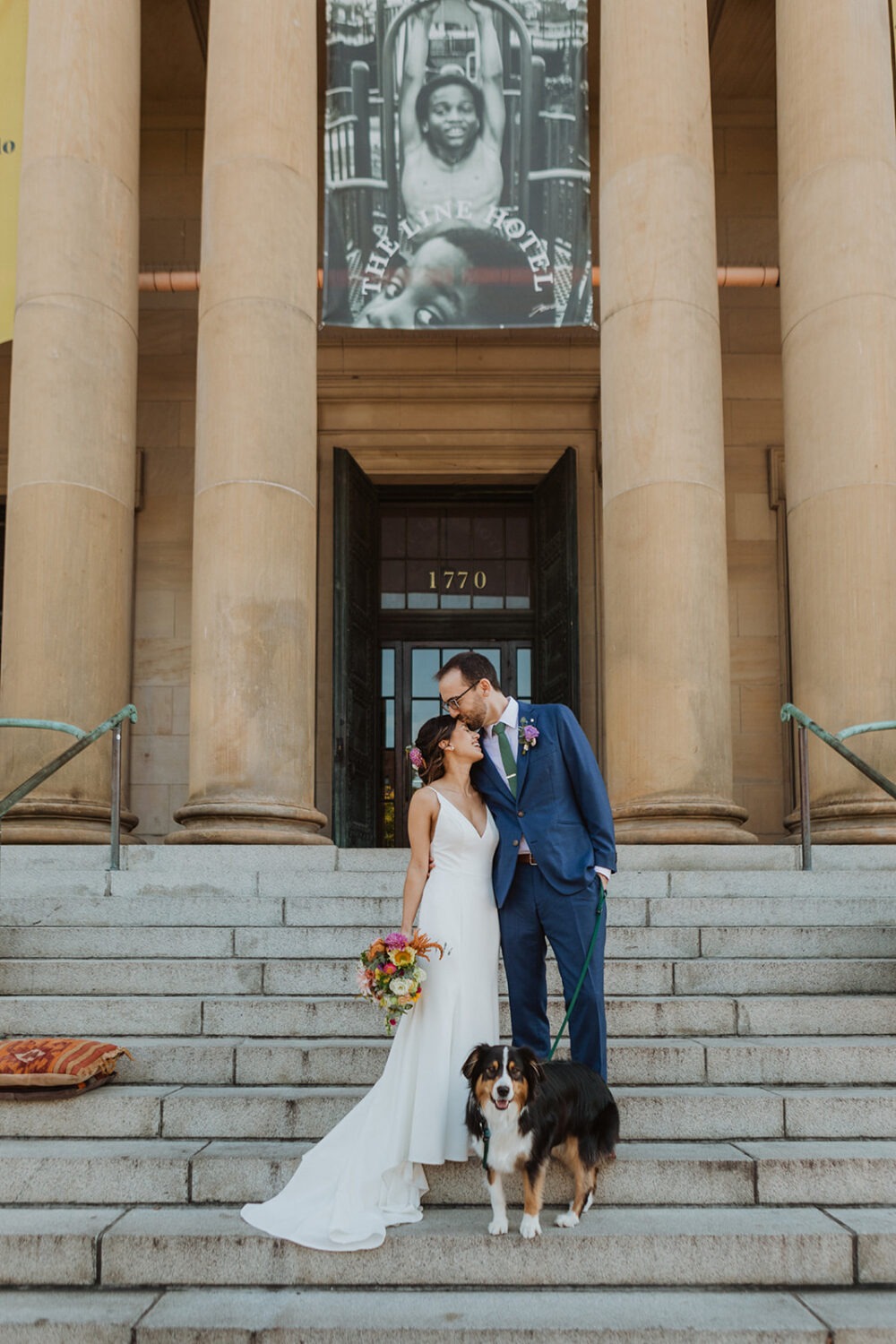 couple posing with their dog on their wedding day