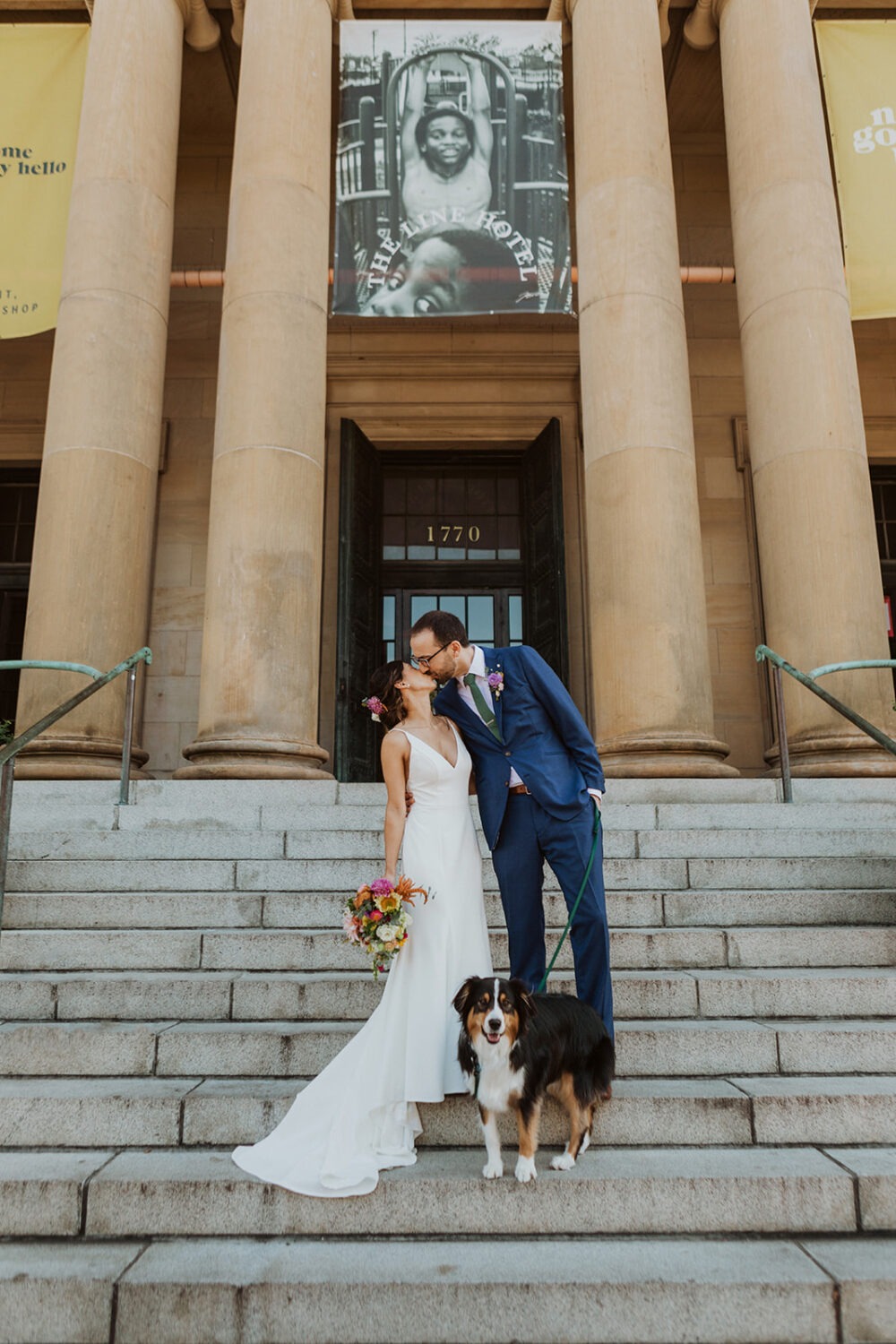 couple kissing while posing with dog on steps