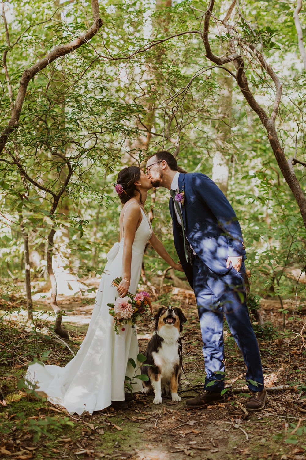 couple kissing with dog looking up at them