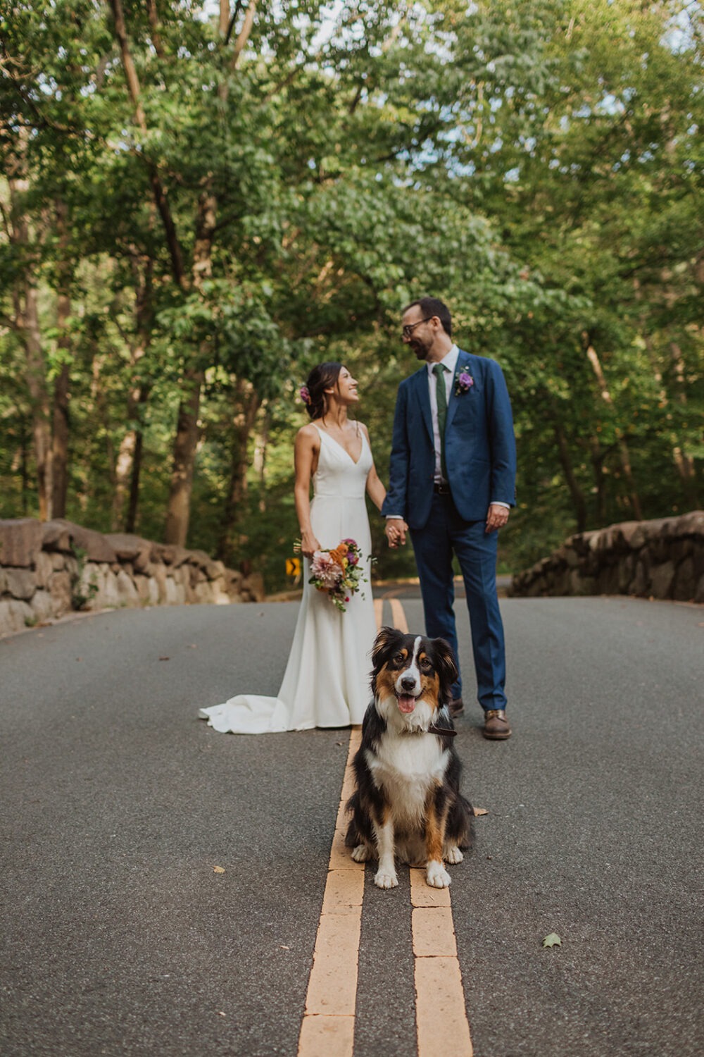 couple posing with their dog in the middle of the road