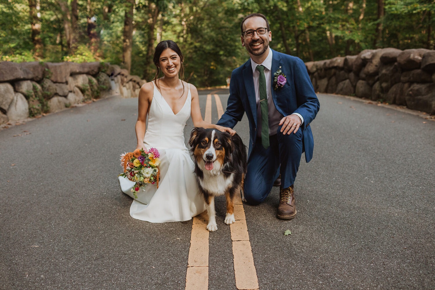 couple posing with their dog in the middle of the road