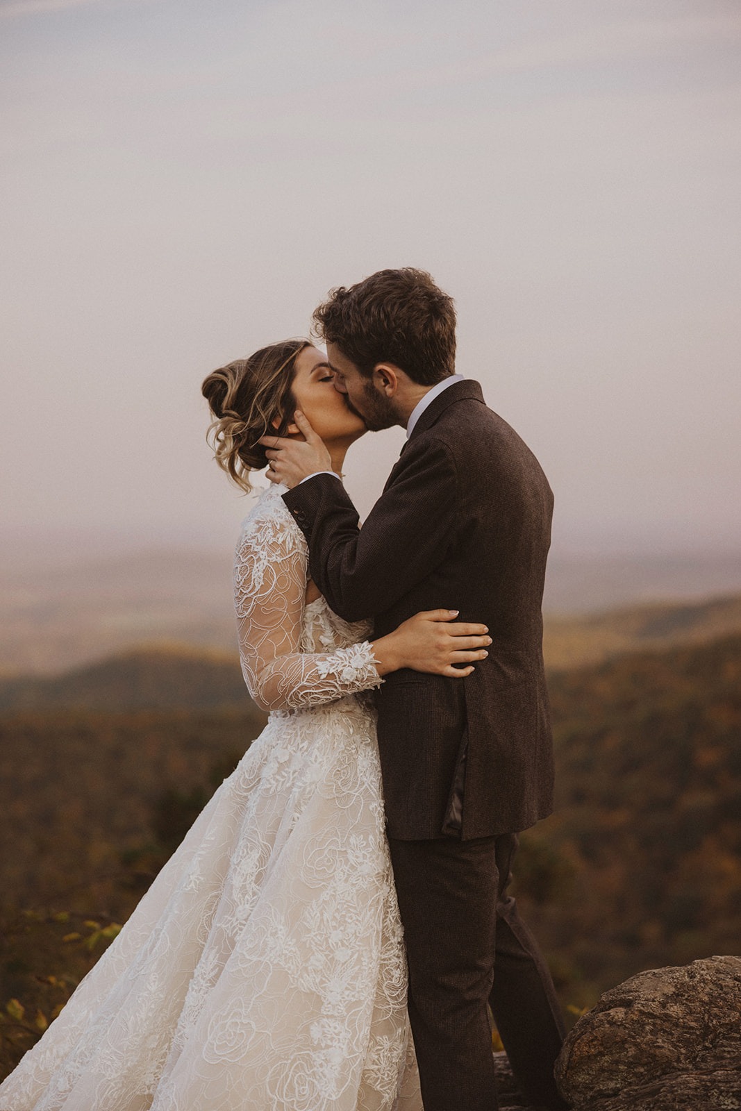 couple kiss in front of mountain views of Shenandoah National Park for pre-wedding photos