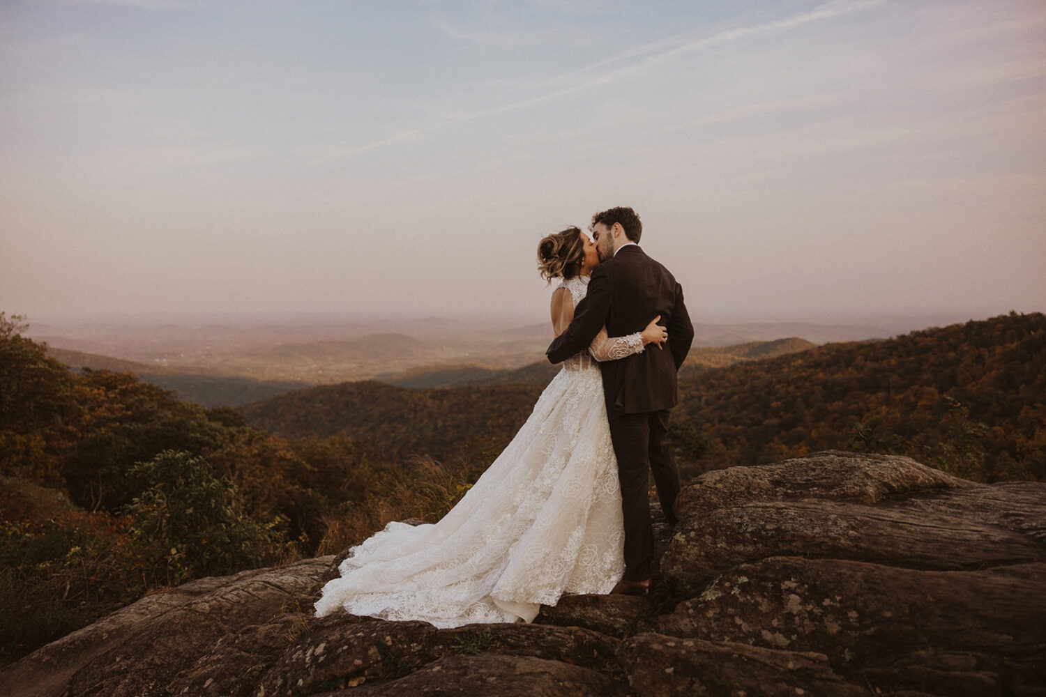 couple kiss in front of mountain views of Shenandoah National Park for pre-wedding photos