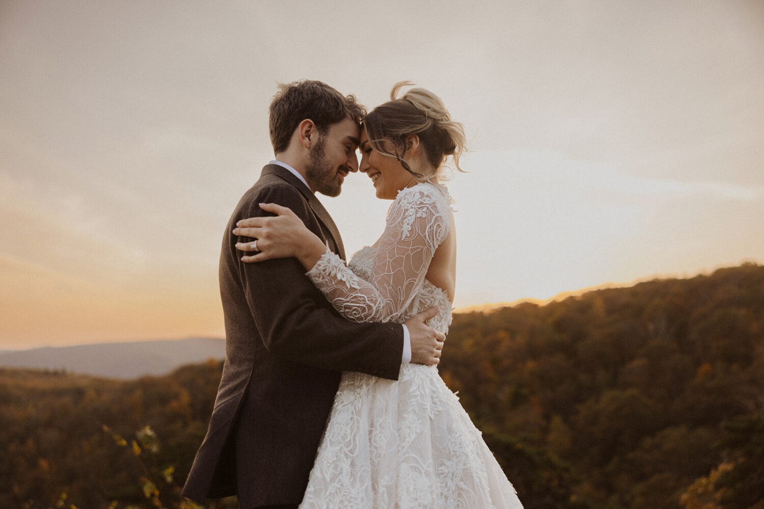 couple kisses during sunset with mountains in the background