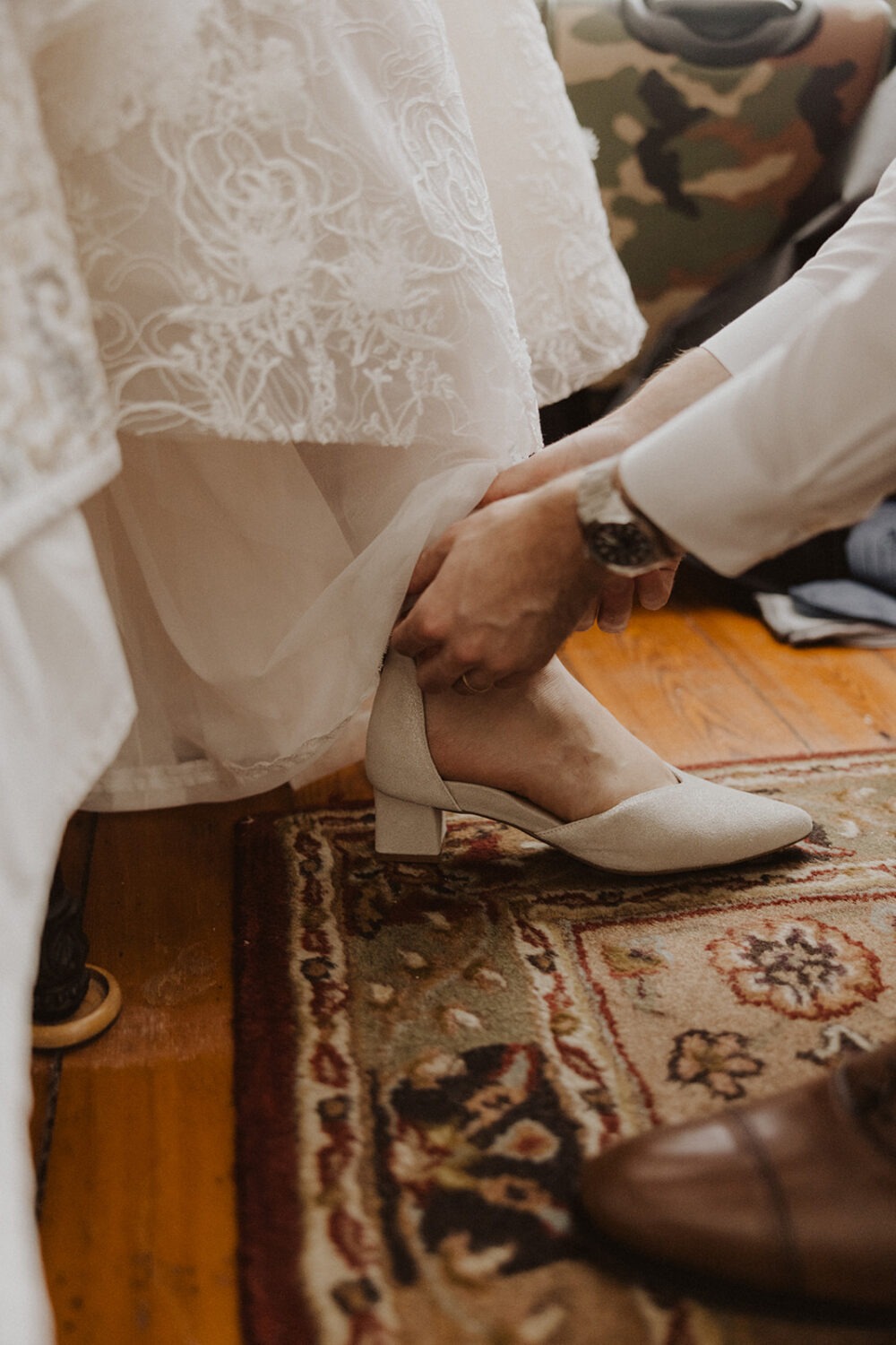 groom helping bride put on shoes for pre-wedding photos