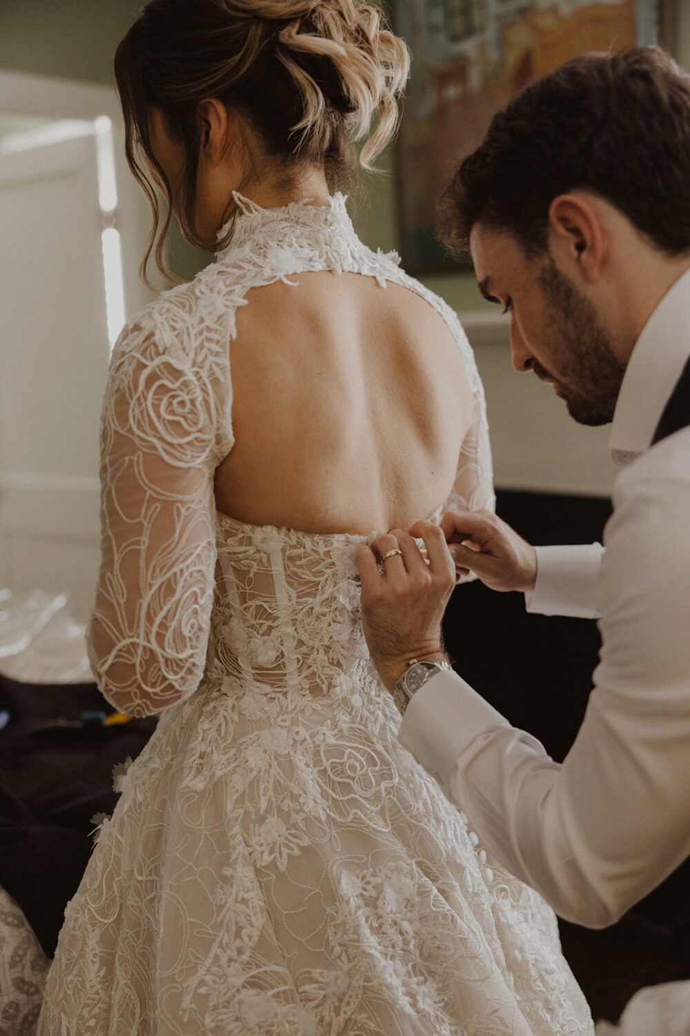 groom helping bride with dress for pre-wedding photos