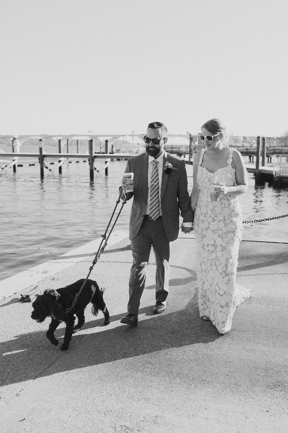 couple walks dog along path beside river