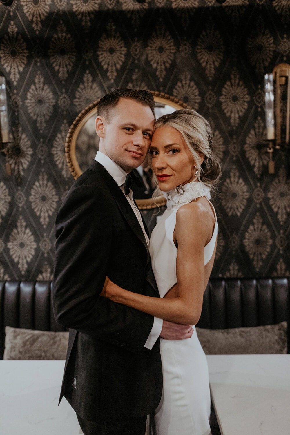 couple poses in front of vintage wall