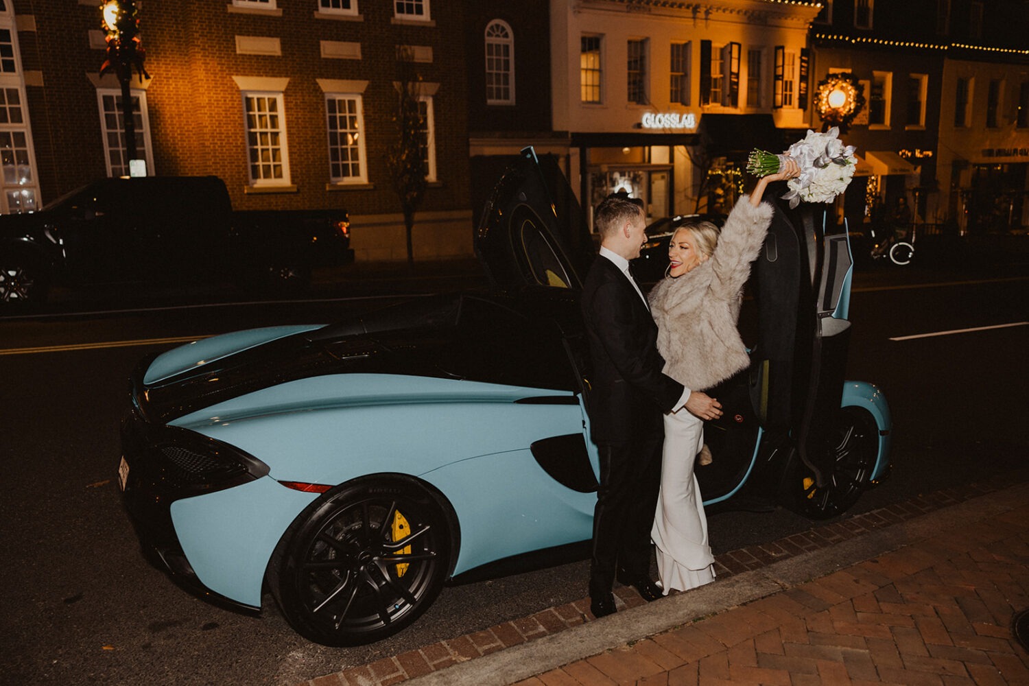 couple poses in front of luxury car