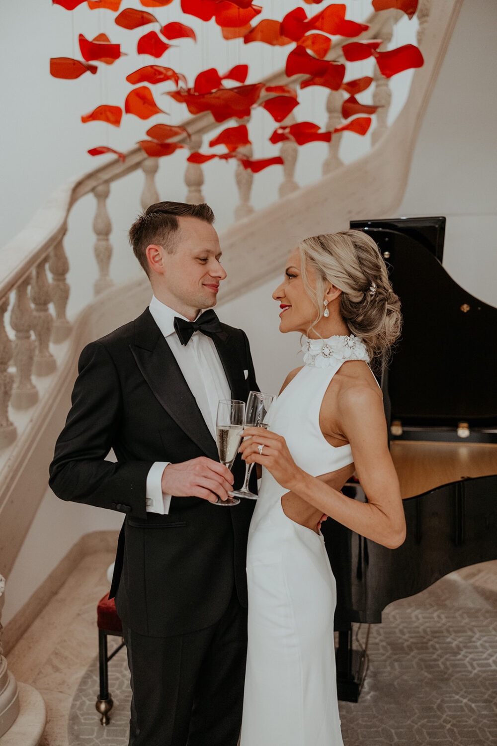 couple poses in front of piano and staircase
