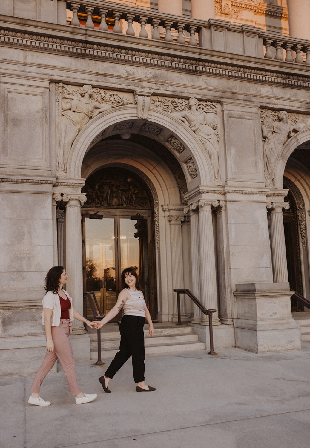 couple walk holding hands in front of the Library of Congress
