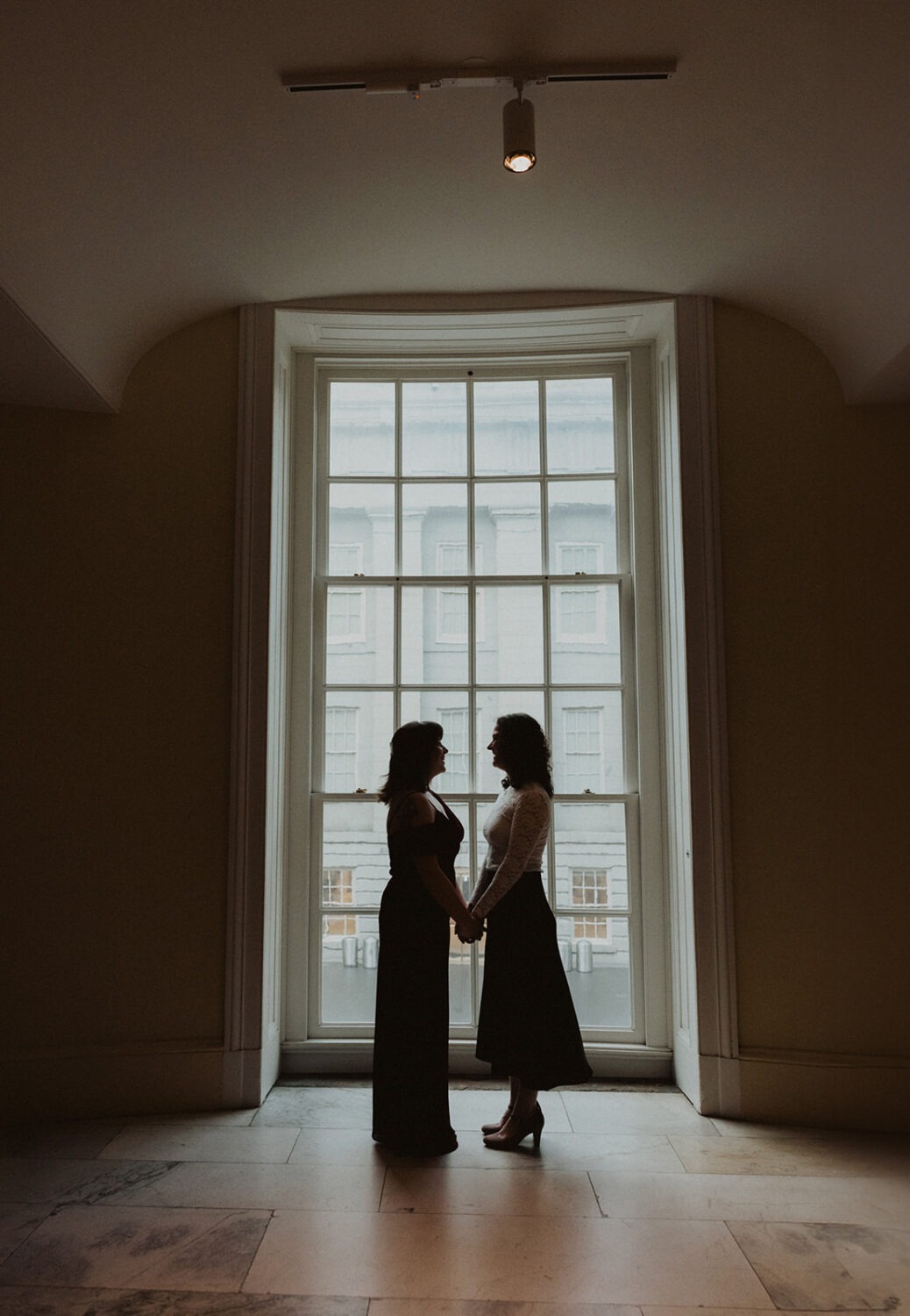 couple pose together in front of large glass window