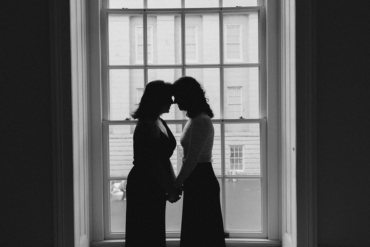 couple pose together in front of large glass window