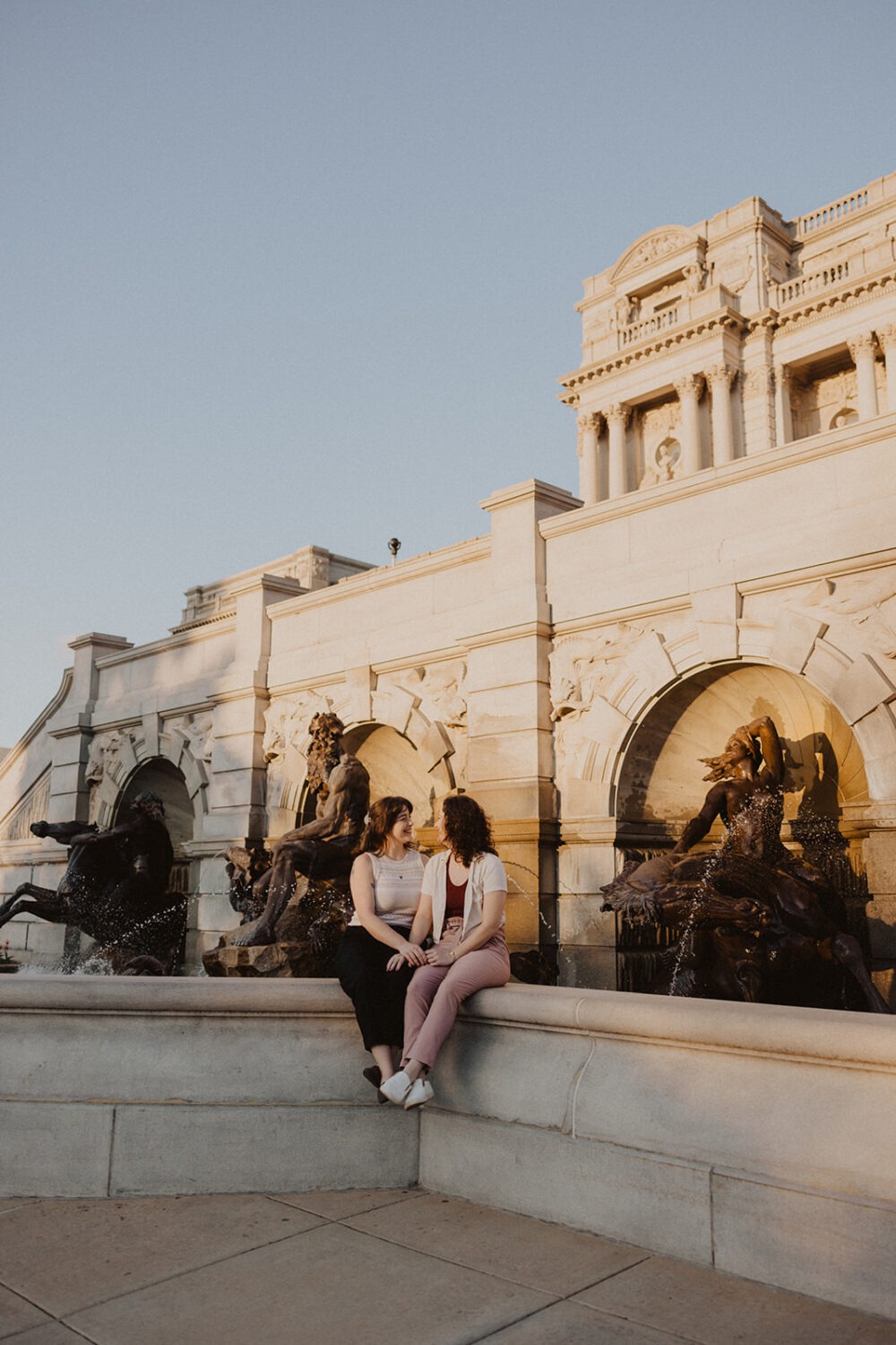 couple sits on ledge during engagement photoshoot