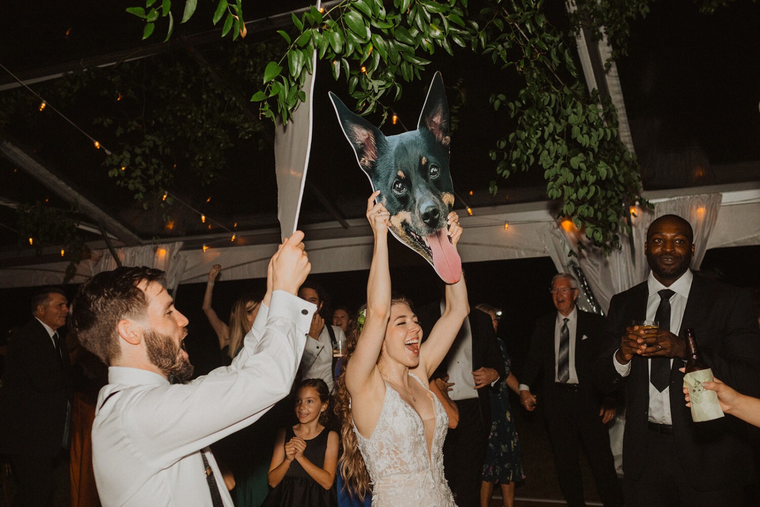 couple holds up blown up face of their dog during reception