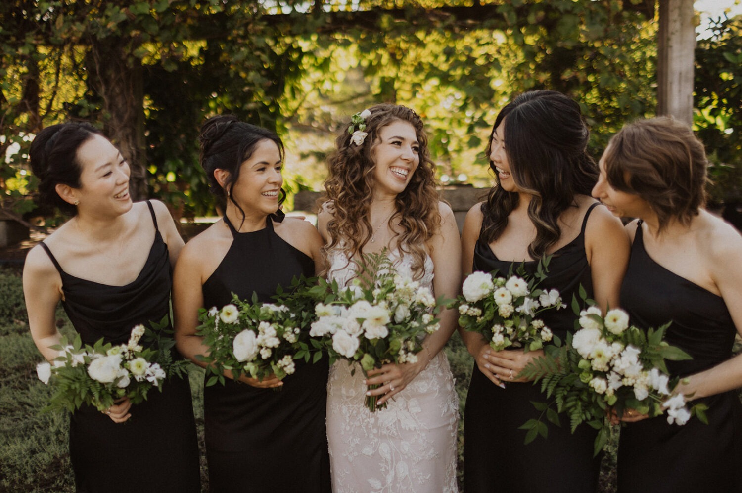 bride and bridesmaids pose with wedding florals