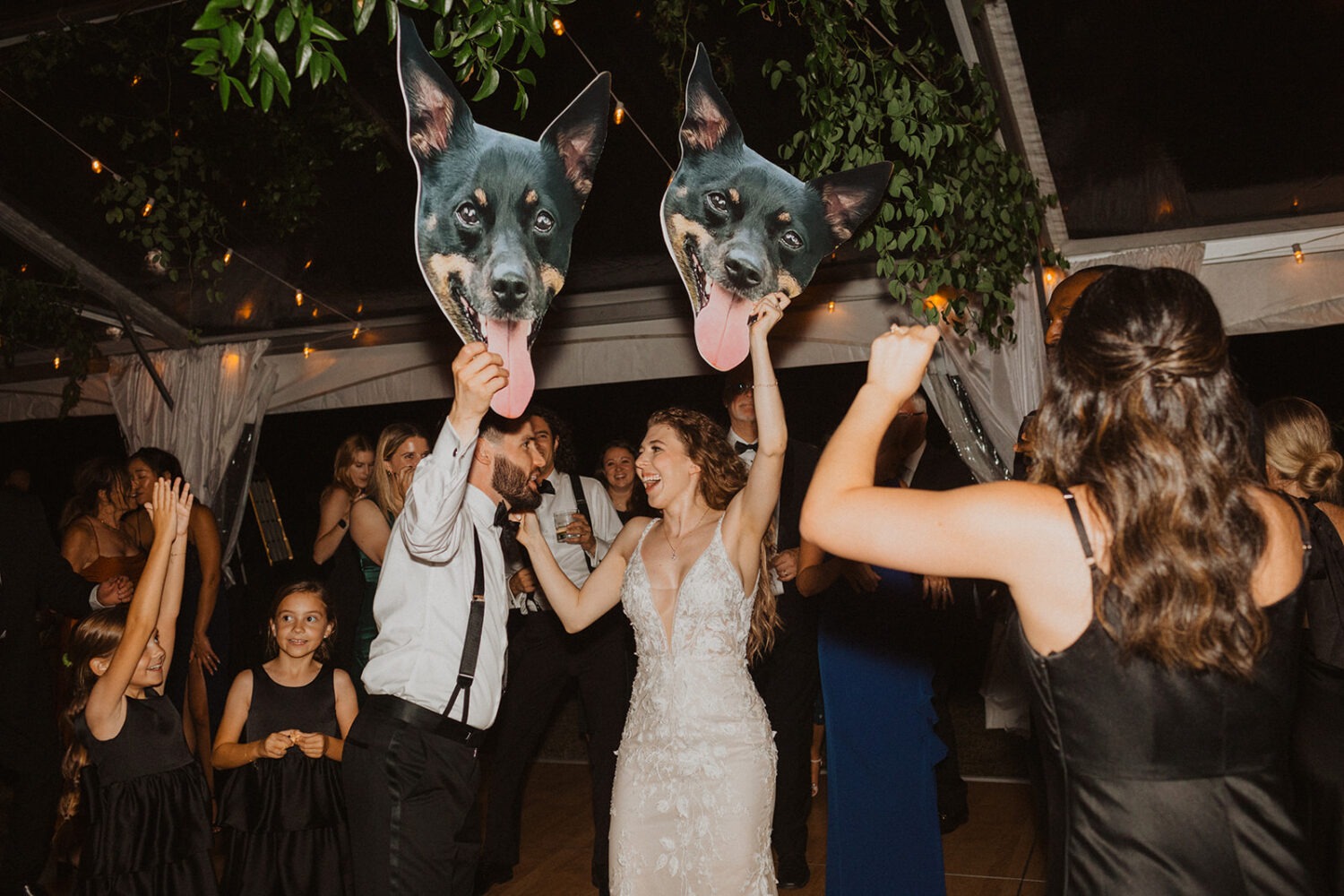 couple holding up blown up signs of their dog during dancing 