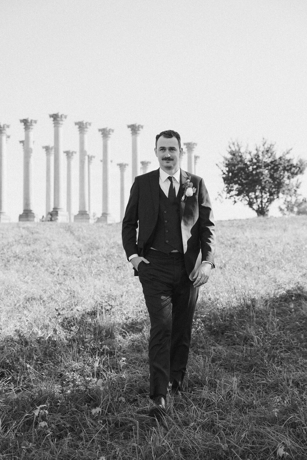 groom poses in front of National Capitol columns