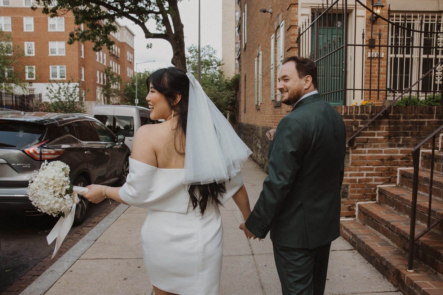 couple hold hands and walk down the city street