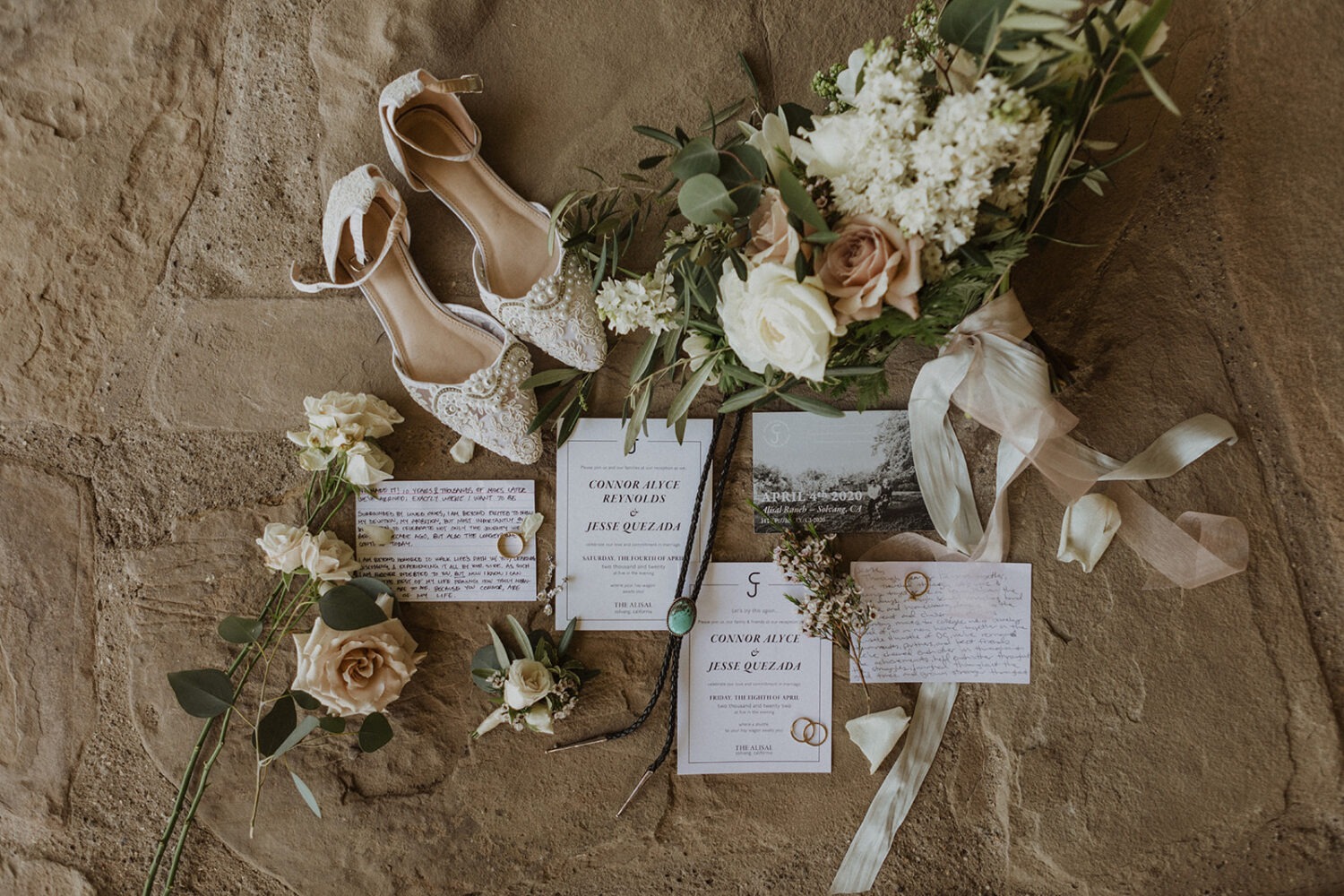 wedding flat lay details with invitation, jewelry, and florals