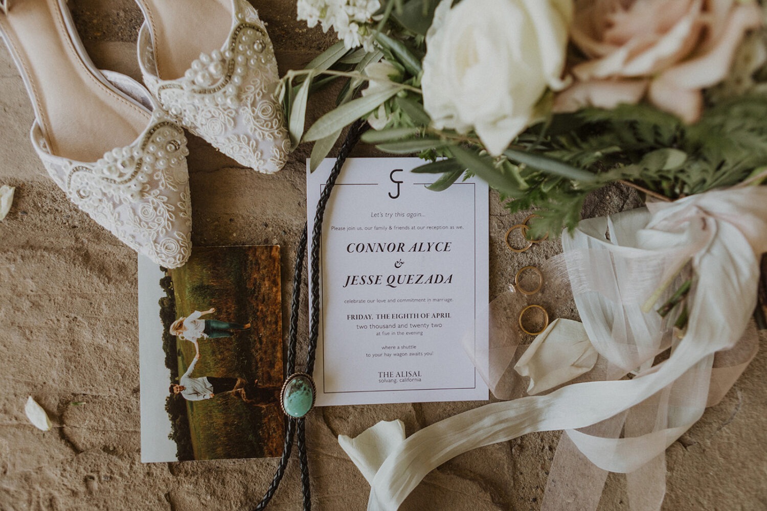 wedding flat lay details with invitation, jewelry, and florals