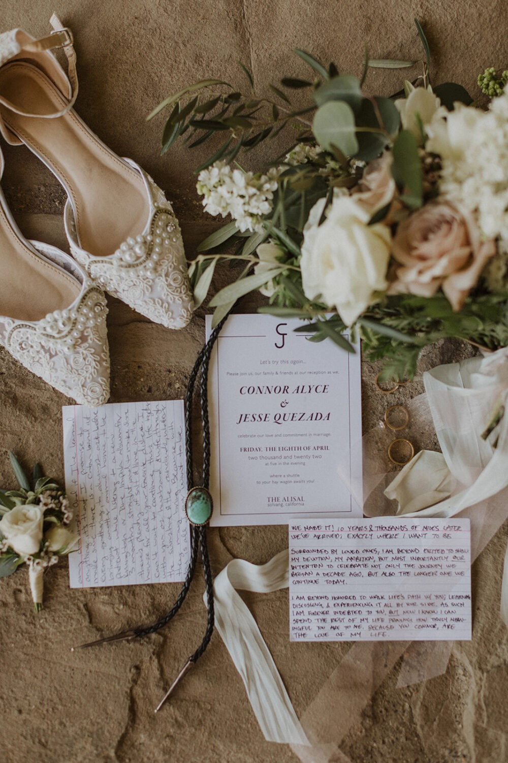 wedding flat lay details with invitation, jewelry, and florals
