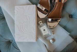 wedding flat lay details of vow book, shoes, and perfume