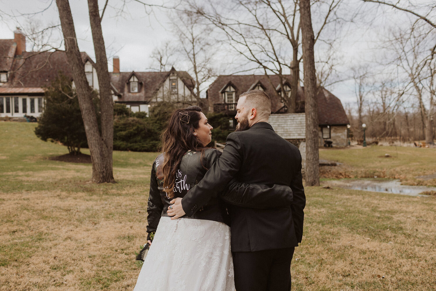 couple embrace showing off custom jacket for bride and the venue