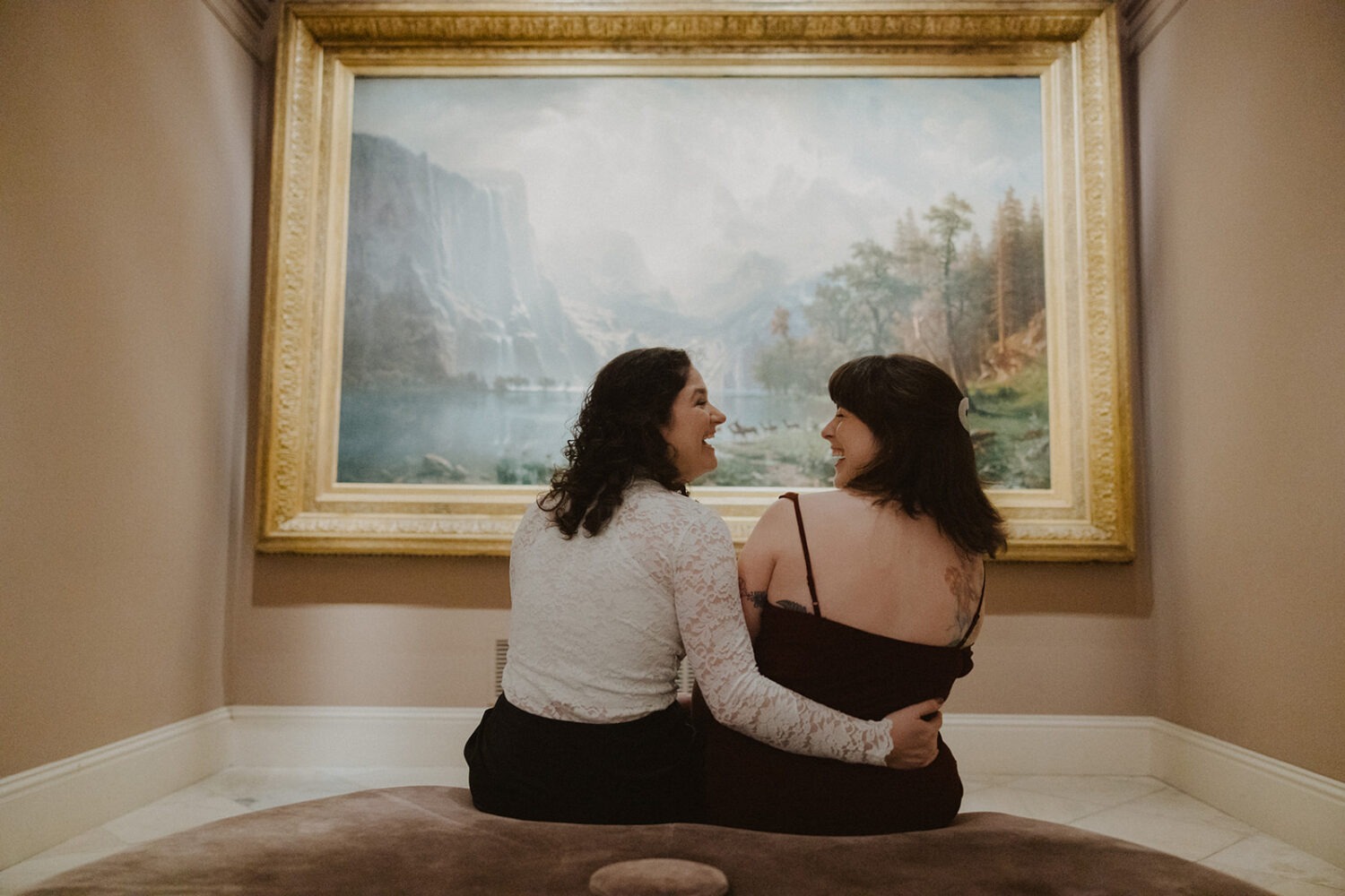 couple sitting and laughing in front of large portrait