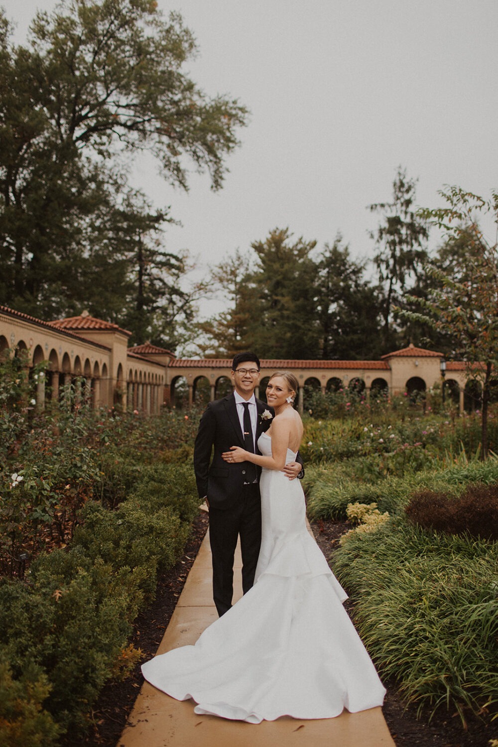 couple pose in front the archways of St. Francis Hall