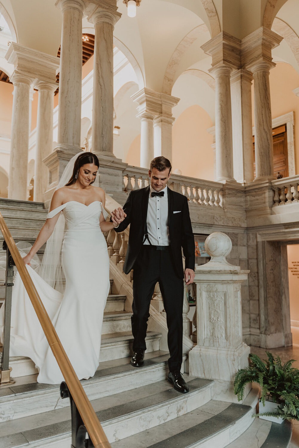 couple holds hands while walking down the stairs