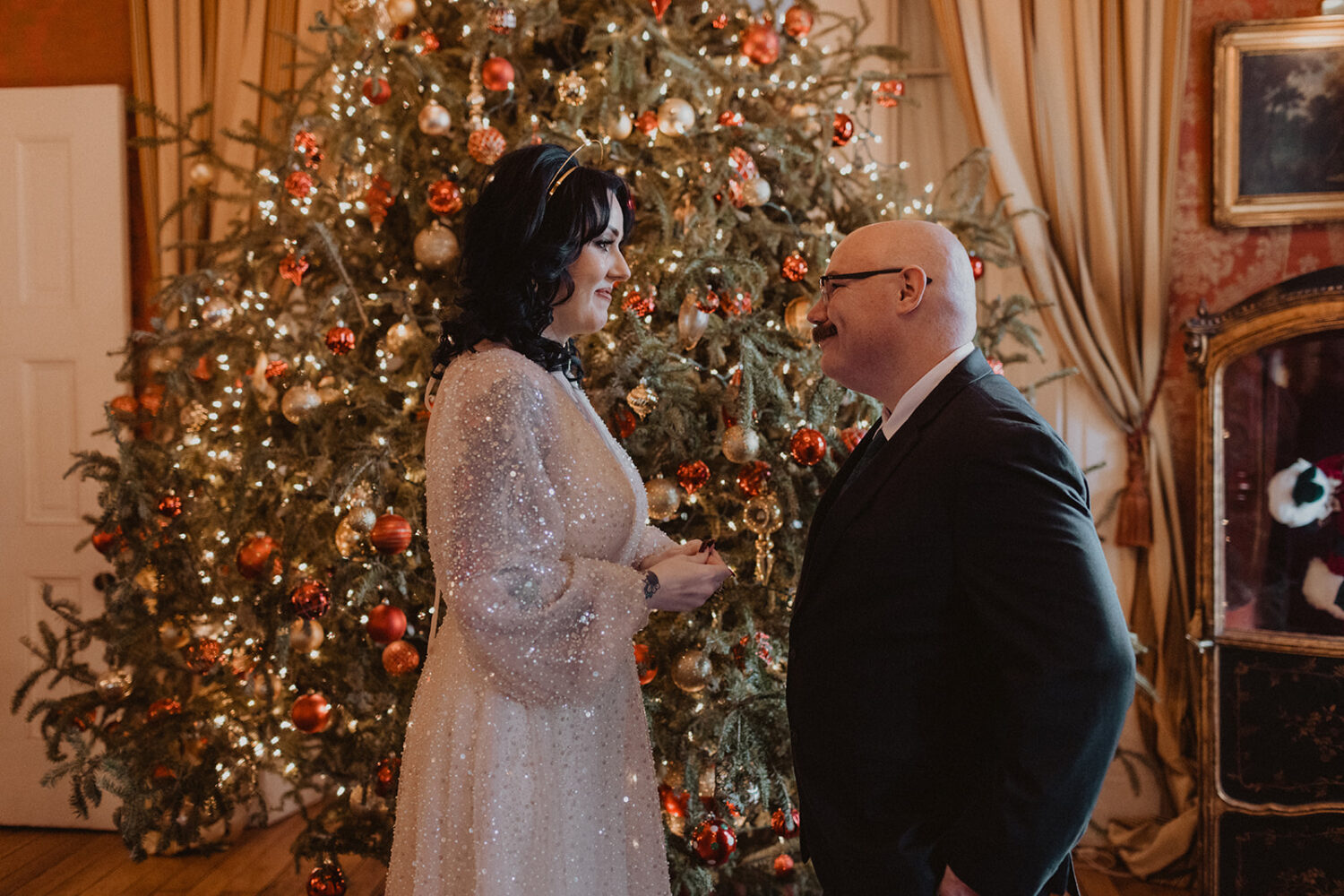 couple looks at each other in front of the Christmas tree