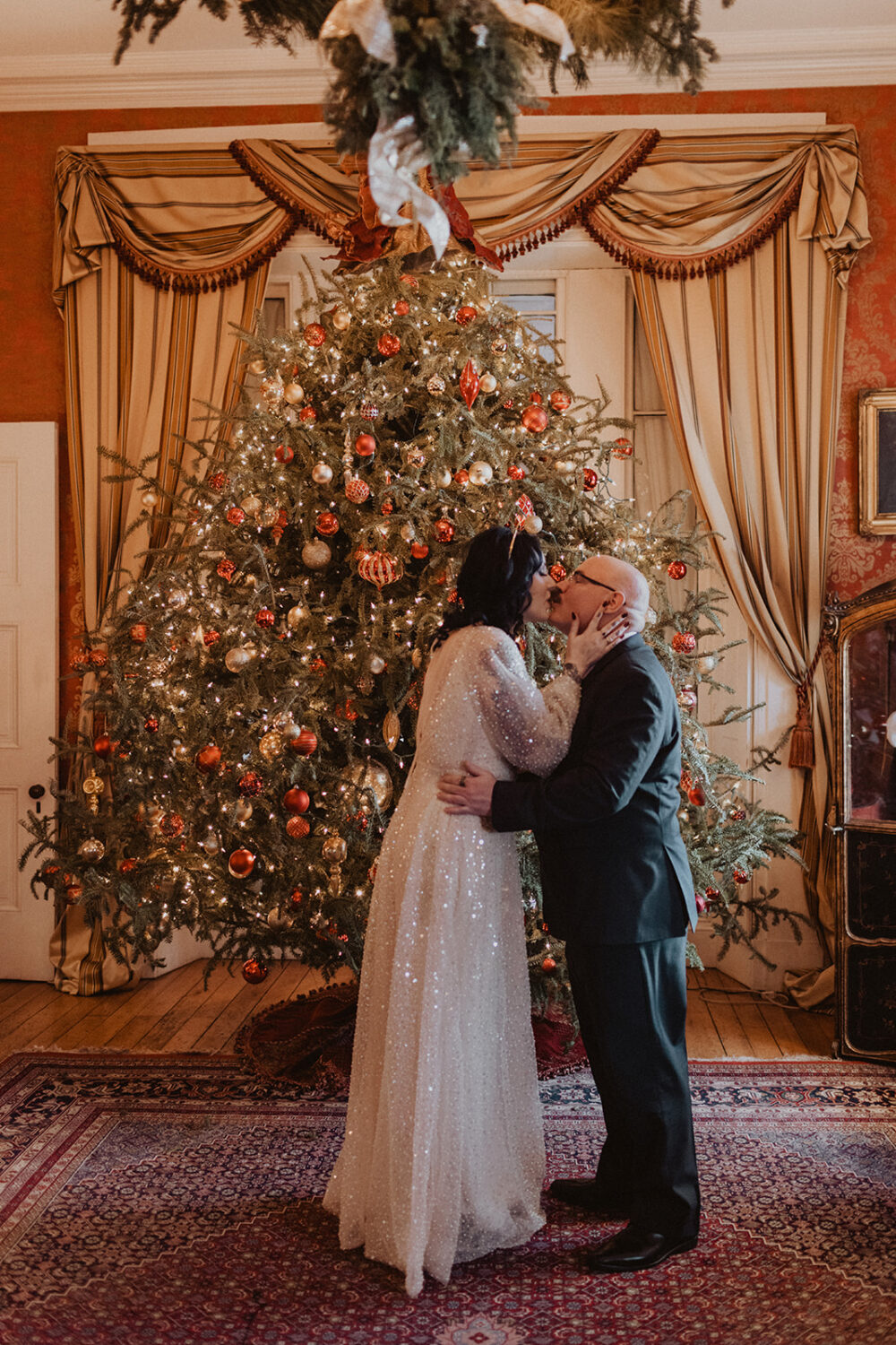 couple kiss in front of Christmas tree