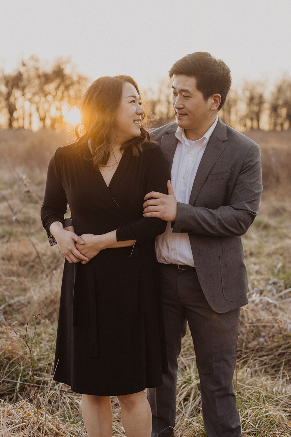 couple embrace while taking winter engagement photos at sunset