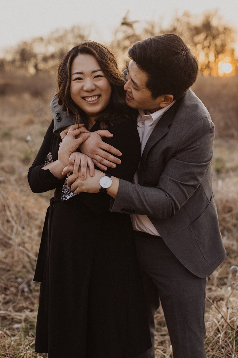 couple embrace in a grassy field at sunset
