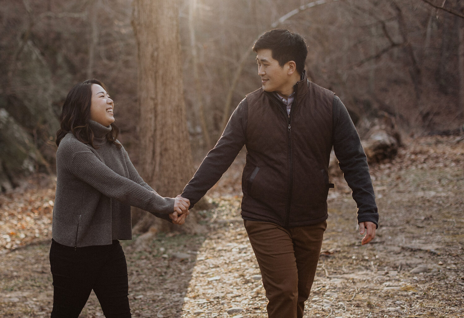 couple hold hands while walking along path in Rock Creek Park