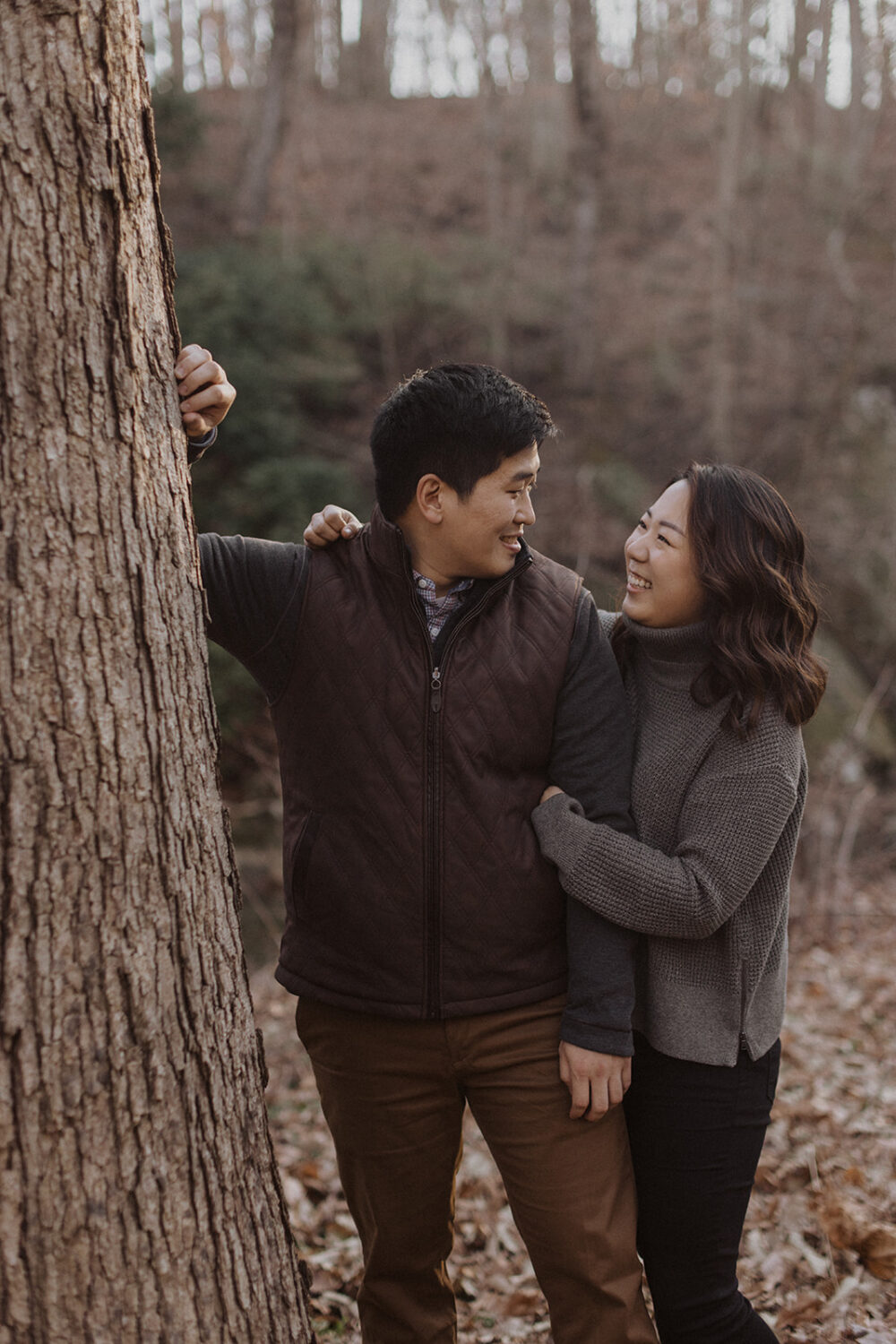 couple embrace while posing by a tree