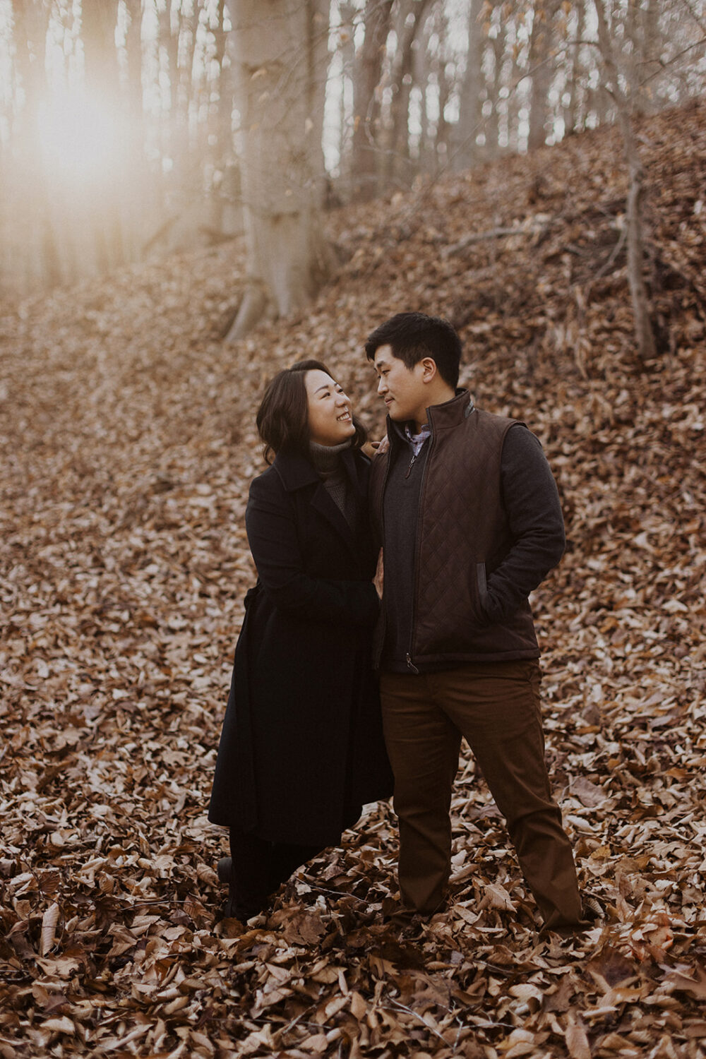 couple embrace while taking winter engagement photos at sunset
