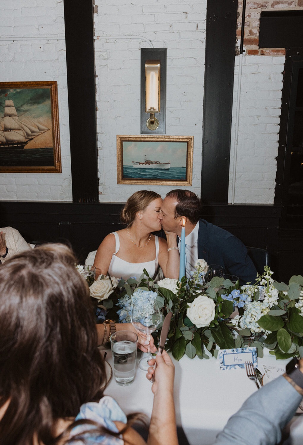 couple kiss during wedding reception dinner