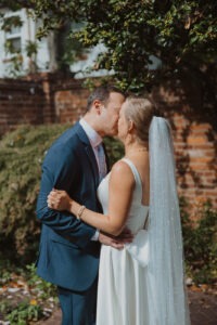 couple kisses under trees during wedding first look
