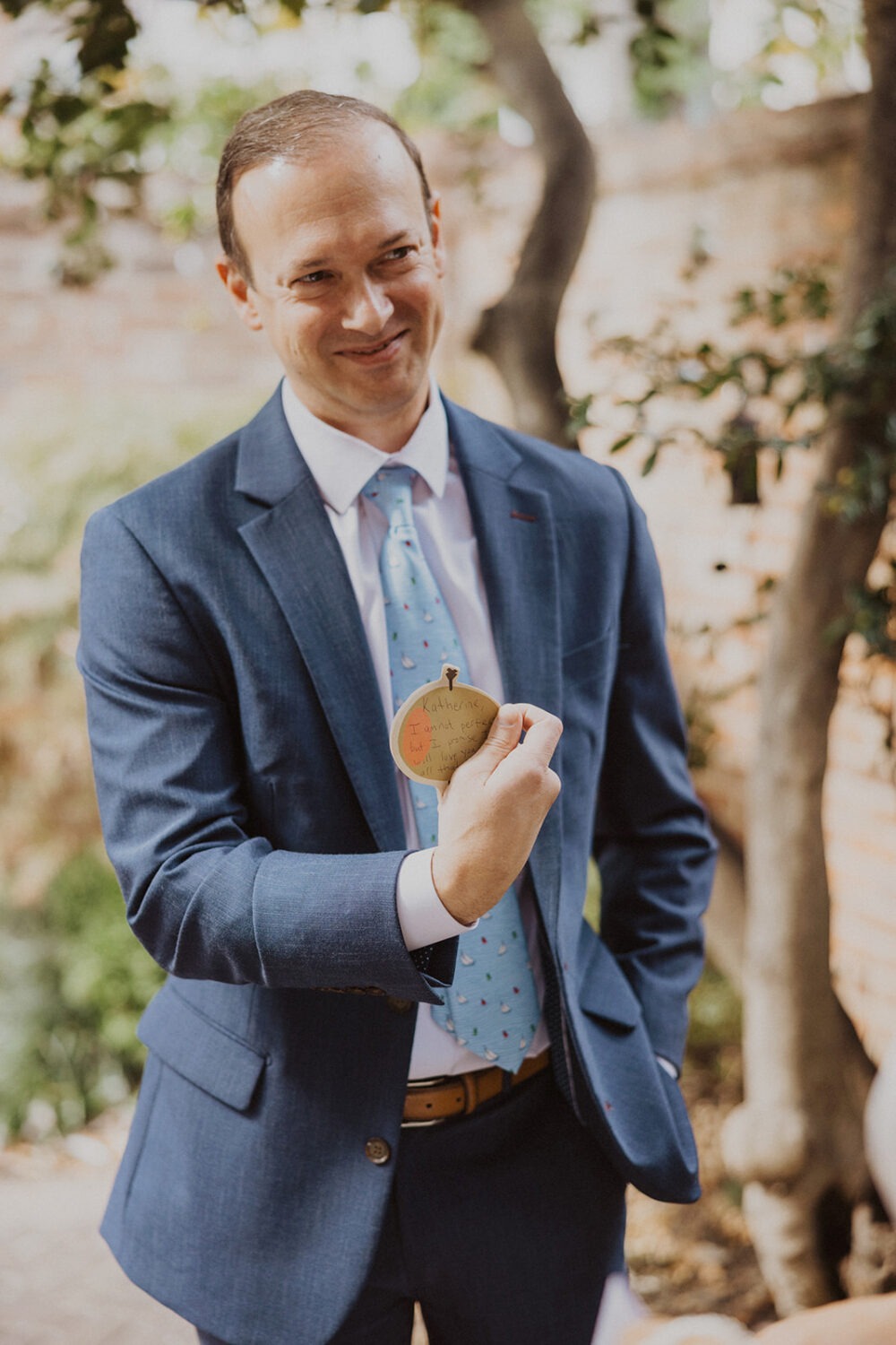 groom holding up wedding vows written on a Post It note