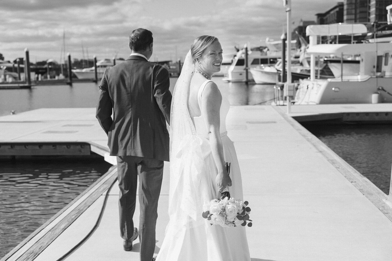 couple walk together holding hands at boating dock