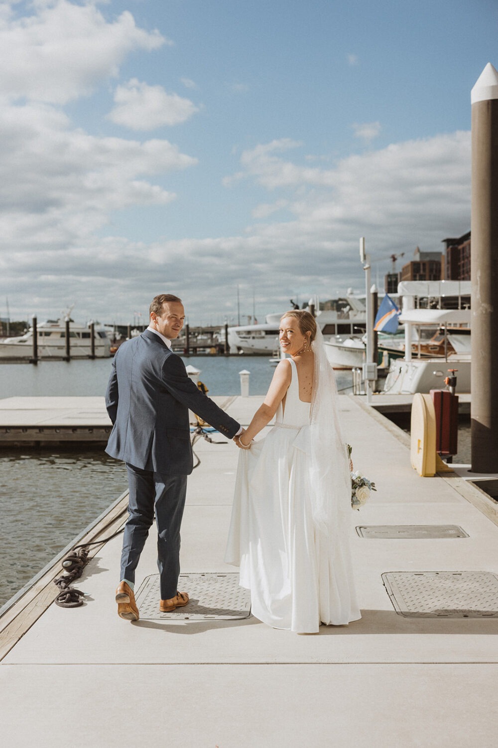 couple walk together holding hands at boating dock