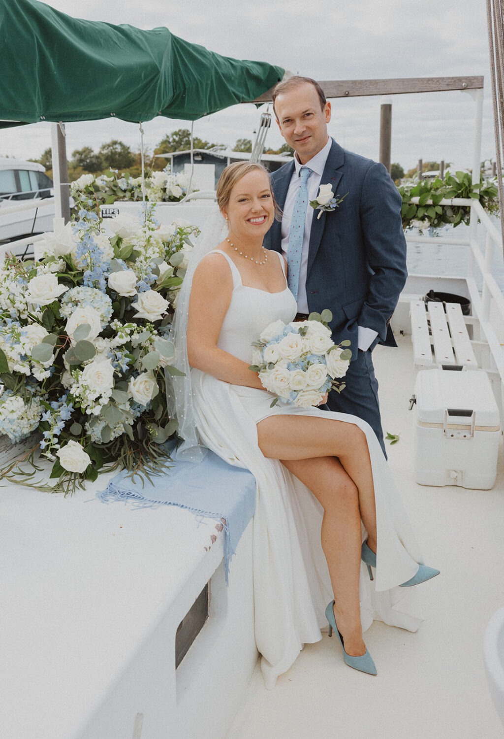 couple pose on the boat surrounded by blue and white flowers