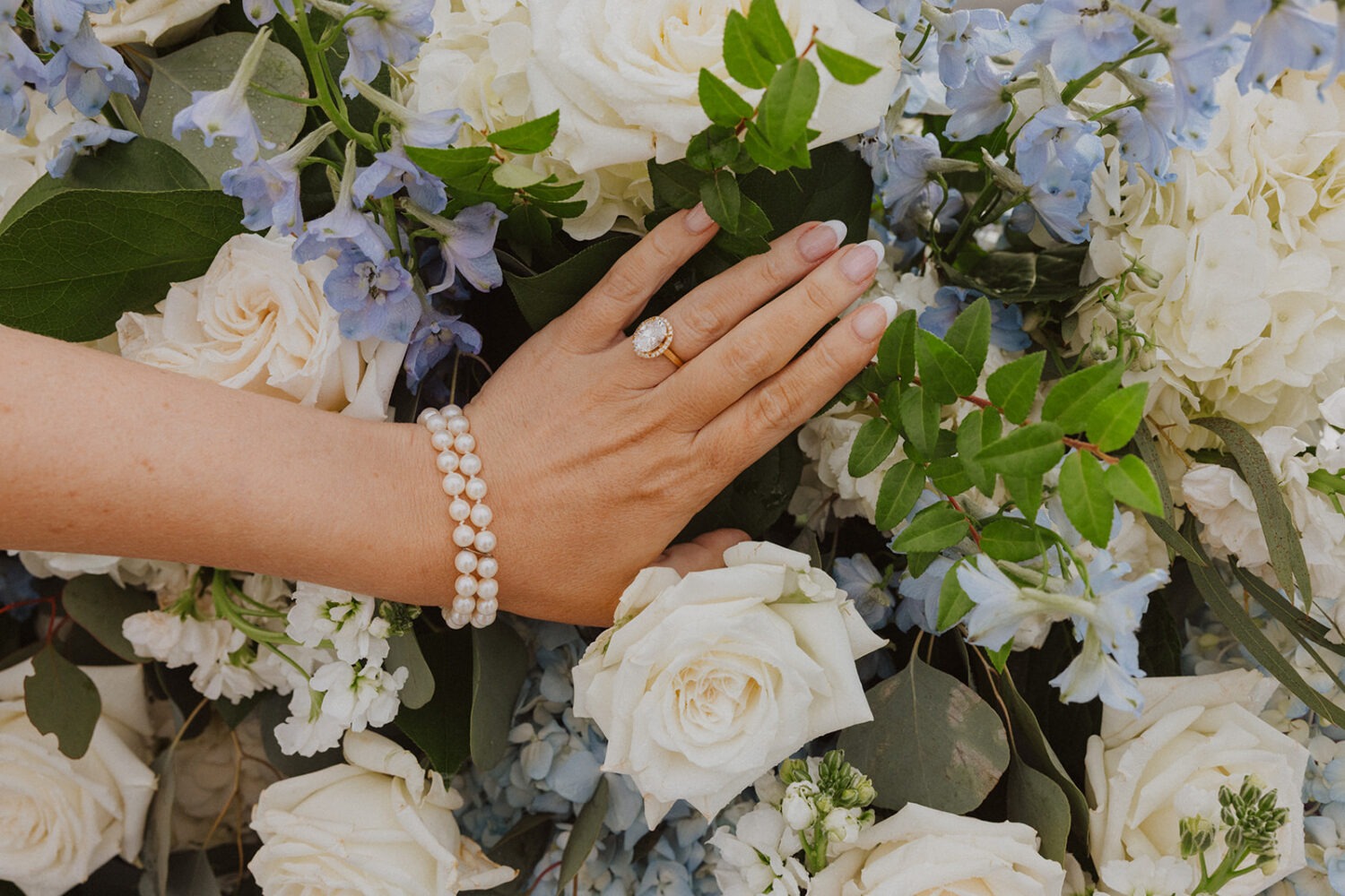 detail shot of engagement ring among the blue and white wedding florals
