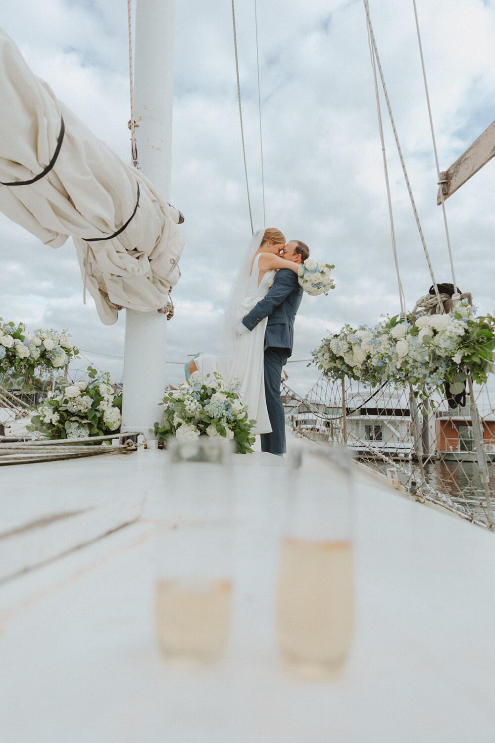 couple kiss on boat surrounded by blue and white flowers