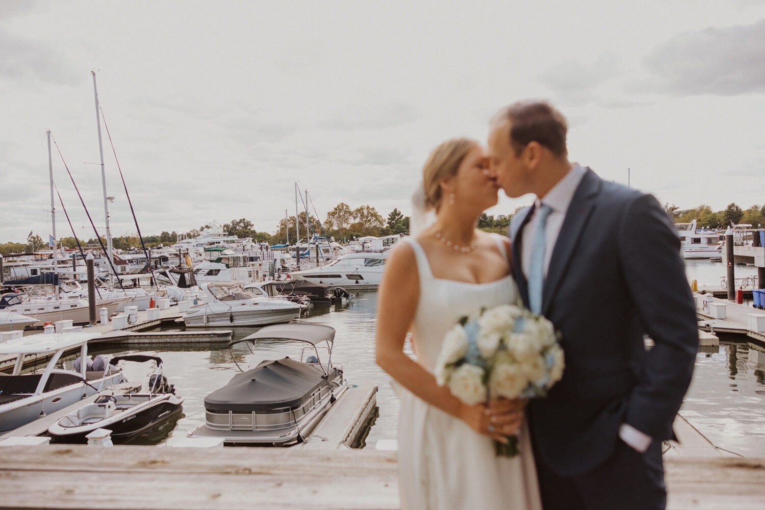 couple kiss on boating dock surrounded by many different boats