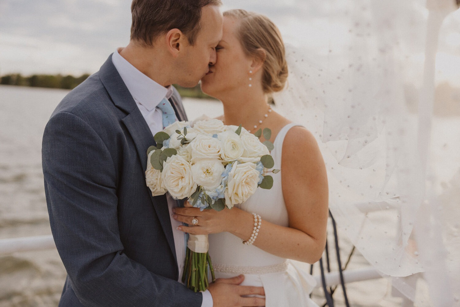 couple kissing holding wedding bouquet